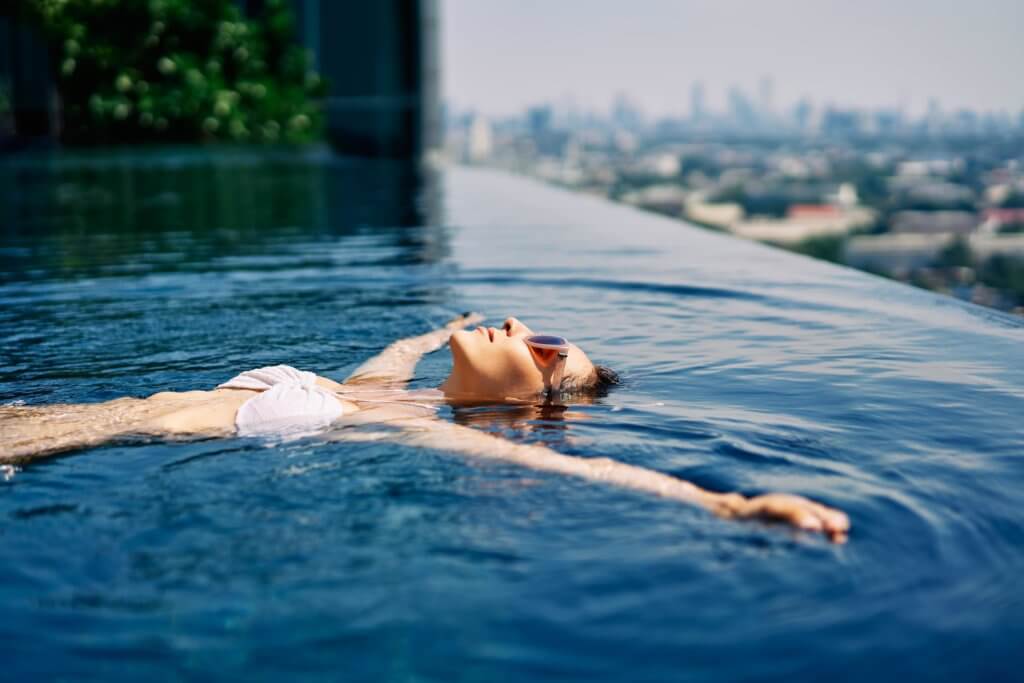 woman floating in pool overlooking city